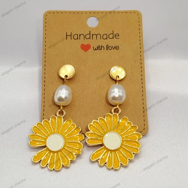 Handmade daisy flower earrings with gold-tone accents and amber crystal beads, displayed on a craft paper card.