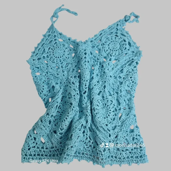 Handmade blue crochet lace top laid flat, showcasing detailed lacework and tie-up shoulder straps.