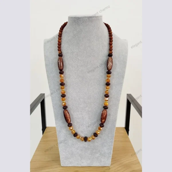 Handmade wooden beaded necklace with ceramic and crystal accents, displayed on a gray bust stand.