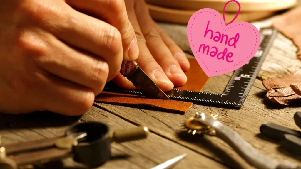 Hands crafting handmade leather item in UAE with handmade heart label