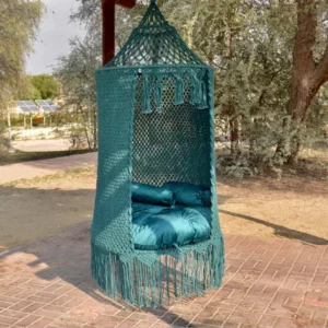 Handmade deep blue macramé swing chair with blue cushions hanging outdoors