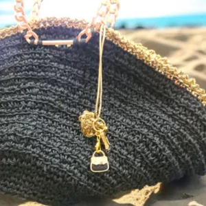 Close-up of golden heart-led charm on black raffia crochet bag